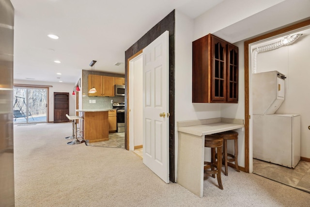 kitchen with recessed lighting, stainless steel appliances, light countertops, decorative backsplash, and a kitchen bar