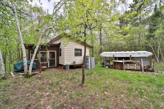 back of house featuring a forest view and a lawn