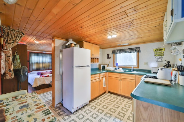 kitchen with dark countertops, wood ceiling, freestanding refrigerator, light floors, and a sink