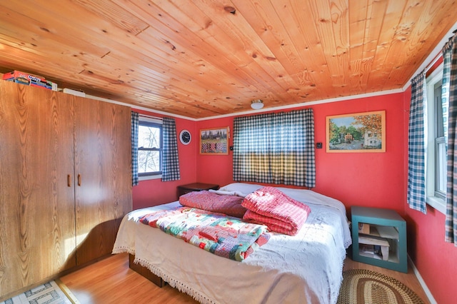 bedroom featuring wood ceiling, crown molding, baseboards, and wood finished floors