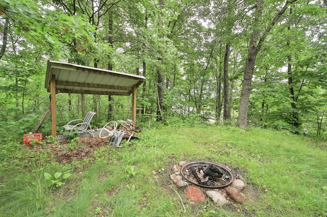 view of yard with an outdoor fire pit and a view of trees