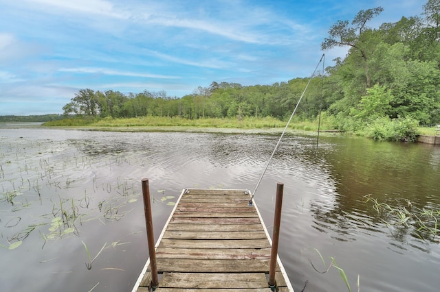 view of dock with a water view and a wooded view