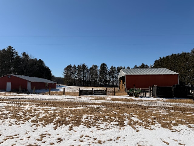 snowy yard with a detached garage, a pole building, and an outdoor structure