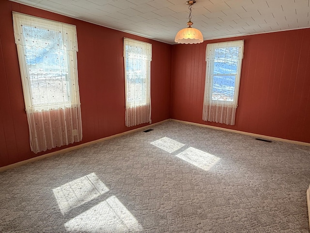 carpeted spare room with baseboards and visible vents