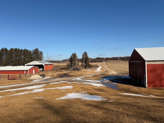 view of yard with dirt driveway, an outbuilding, fence, and a detached garage