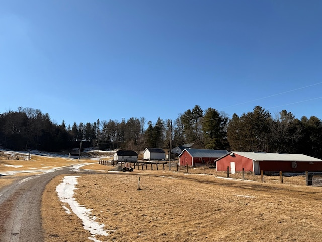 exterior space with driveway, a garage, an outbuilding, a pole building, and fence