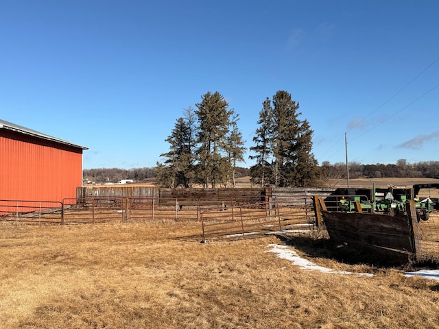 view of yard featuring a pole building, a rural view, an outdoor structure, and fence