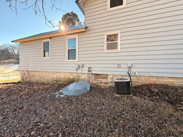 view of side of home featuring central AC and metal roof