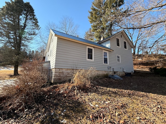 rear view of property featuring metal roof and central AC