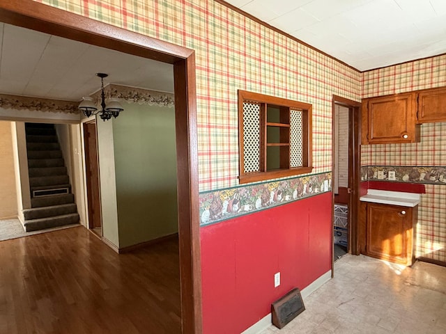 kitchen featuring a chandelier, wood finished floors, brown cabinets, and wallpapered walls