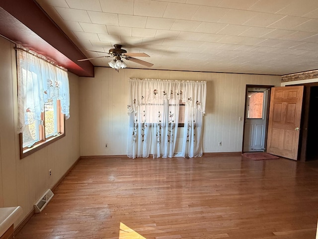 unfurnished room with baseboards, wood finished floors, visible vents, and a ceiling fan