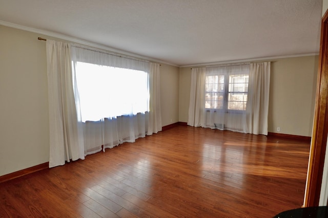 empty room with ornamental molding, baseboards, and hardwood / wood-style flooring