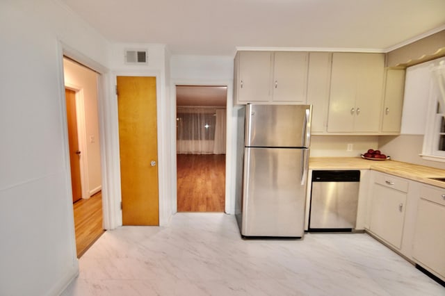 kitchen with visible vents, crown molding, light countertops, appliances with stainless steel finishes, and marble finish floor