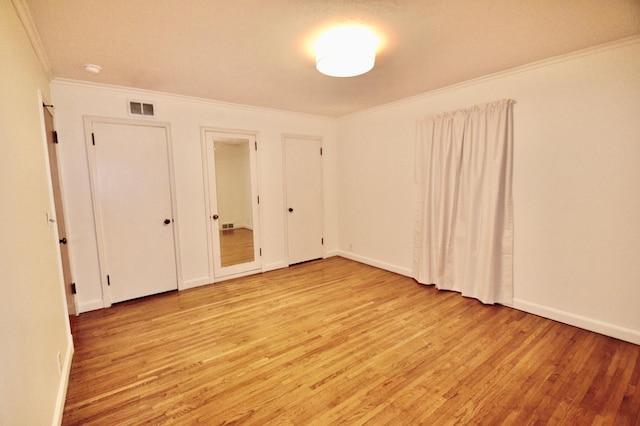 unfurnished bedroom with crown molding, light wood-style floors, visible vents, and baseboards