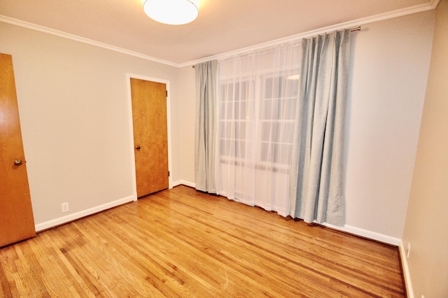 unfurnished room featuring crown molding, baseboards, and wood finished floors