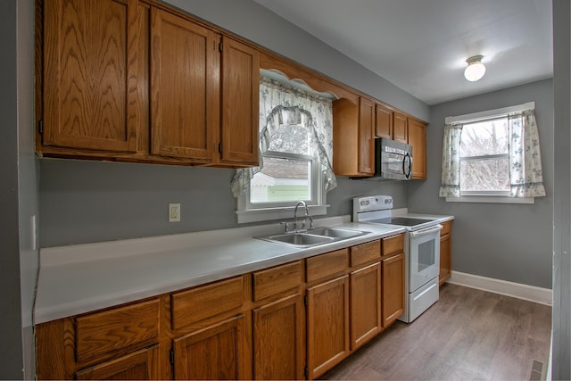 kitchen with black microwave, brown cabinets, a sink, and white range with electric cooktop