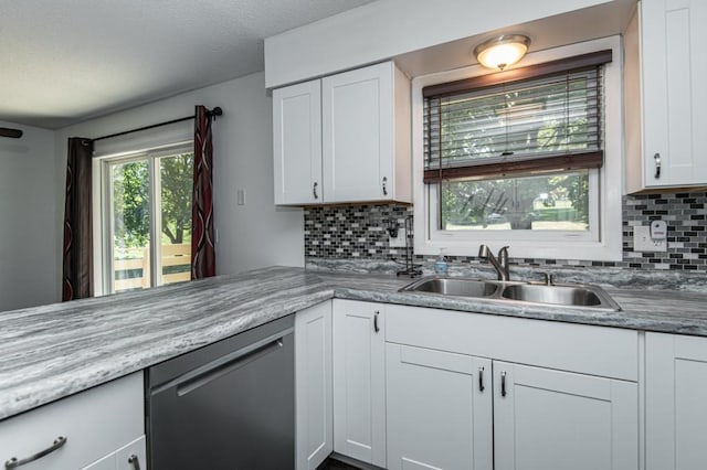 kitchen featuring white cabinetry, dishwashing machine, backsplash, and a sink