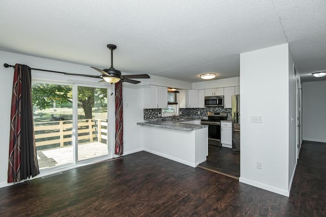 kitchen featuring a peninsula, dark wood-type flooring, appliances with stainless steel finishes, white cabinetry, and backsplash