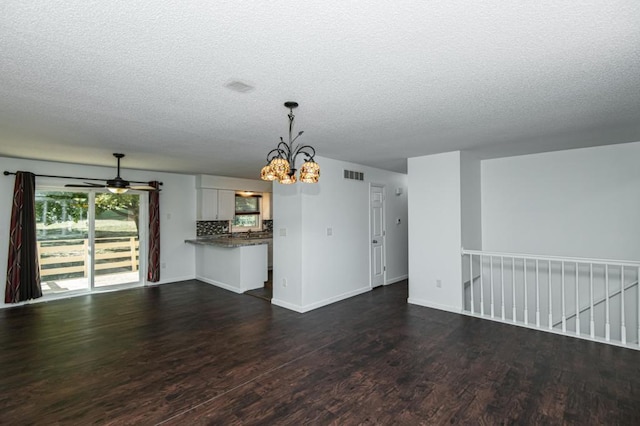 unfurnished living room featuring baseboards, dark wood-type flooring, and a textured ceiling