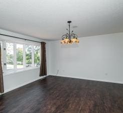 empty room featuring dark wood finished floors and a notable chandelier