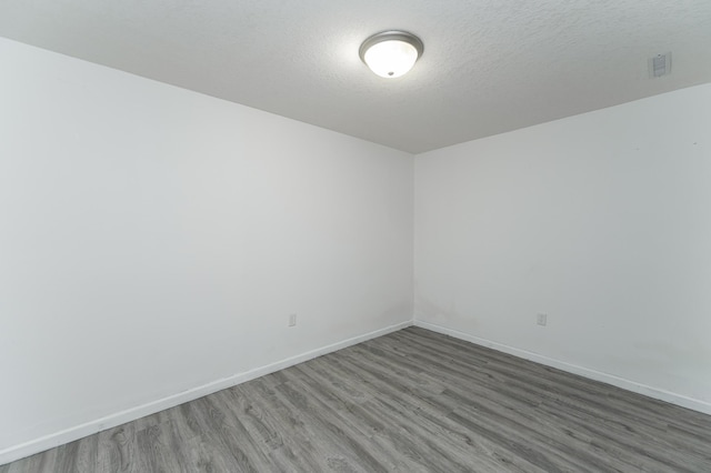 empty room featuring baseboards, a textured ceiling, and wood finished floors