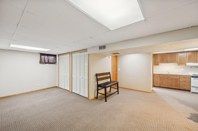 finished basement with light carpet, a paneled ceiling, visible vents, and baseboards