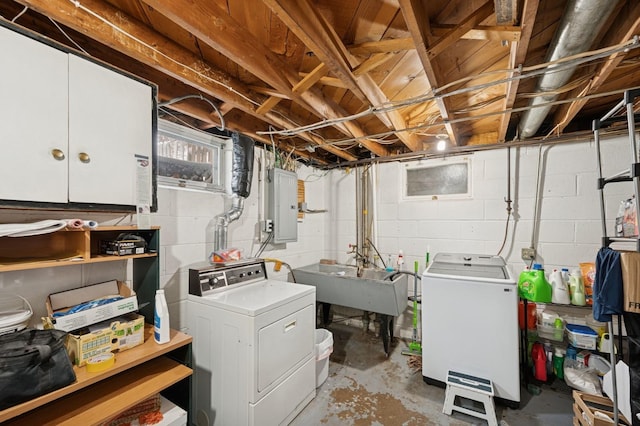 clothes washing area featuring washing machine and dryer, electric panel, cabinet space, and a sink