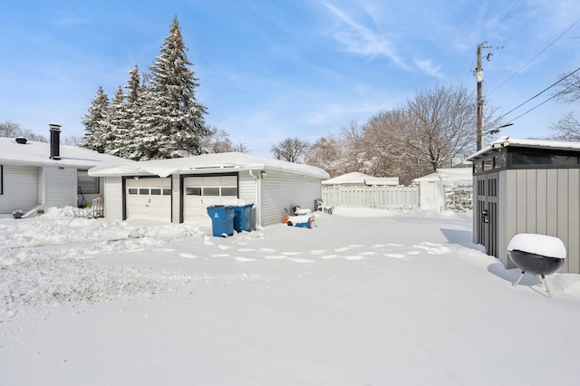 yard layered in snow with a garage, fence, and an outdoor structure