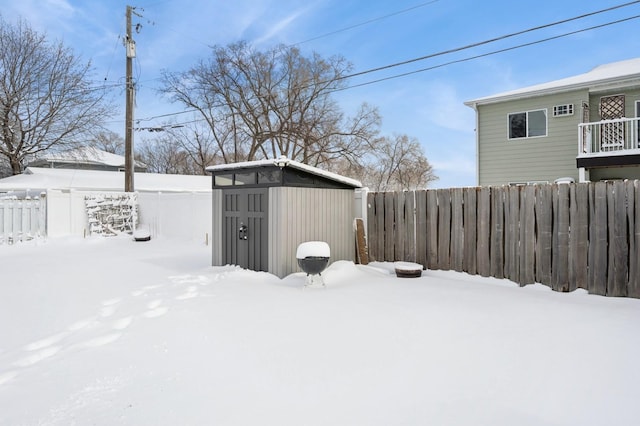 snowy yard with an outbuilding, a shed, and a fenced backyard