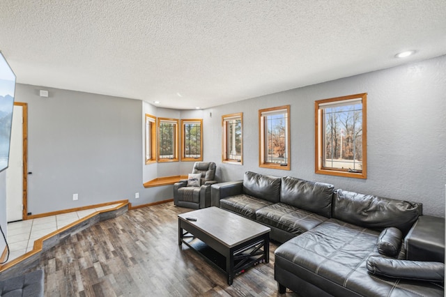 living room with plenty of natural light, a textured ceiling, baseboards, and wood finished floors