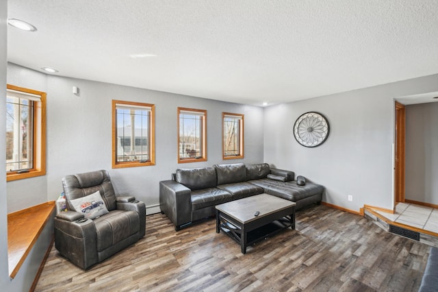 living room featuring baseboards, wood finished floors, a baseboard radiator, and a textured ceiling