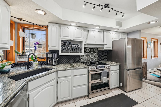 kitchen featuring tasteful backsplash, visible vents, custom range hood, stainless steel appliances, and a sink