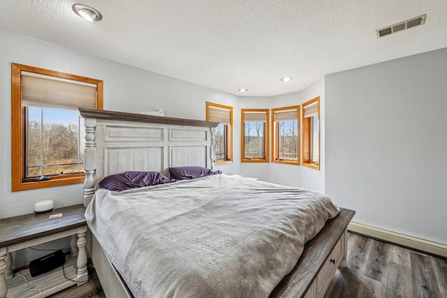 bedroom featuring visible vents, recessed lighting, wood finished floors, a textured ceiling, and a baseboard radiator