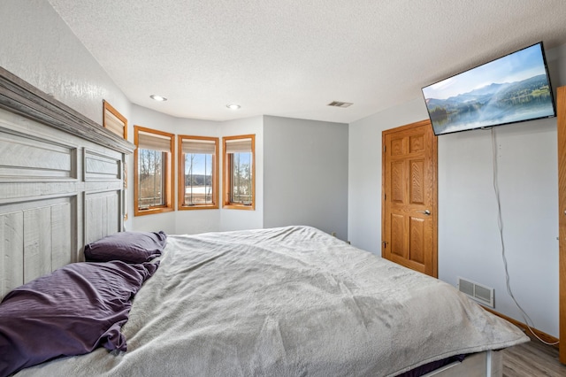 bedroom with recessed lighting, visible vents, a textured ceiling, and wood finished floors