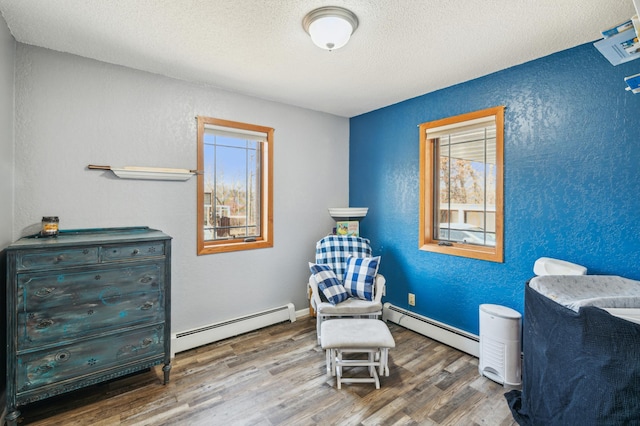 sitting room featuring plenty of natural light, wood finished floors, and a baseboard radiator