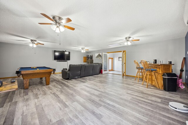 game room featuring a textured ceiling, wood finished floors, pool table, baseboards, and ceiling fan