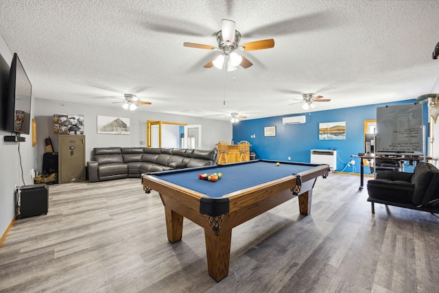 playroom with a textured ceiling, an AC wall unit, wood finished floors, and billiards