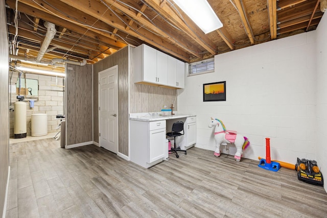 basement featuring light wood-style floors and concrete block wall