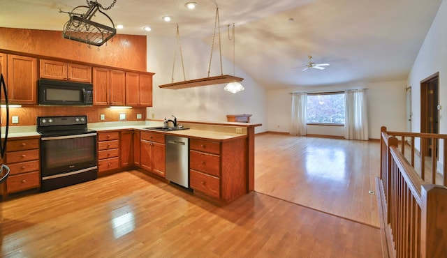 kitchen featuring brown cabinets, a peninsula, black appliances, light countertops, and open floor plan