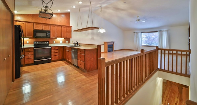 kitchen with brown cabinets, black appliances, light wood-type flooring, and a sink