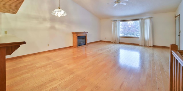 unfurnished living room with baseboards, high vaulted ceiling, light wood-style flooring, ceiling fan, and a glass covered fireplace