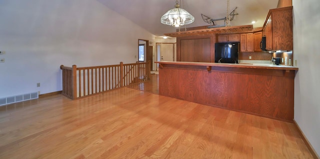 kitchen featuring brown cabinetry, visible vents, a peninsula, black appliances, and light wood-style floors