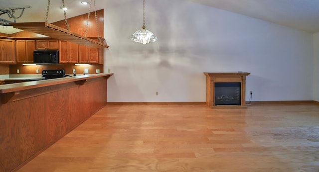 kitchen with black appliances, light wood-style floors, a glass covered fireplace, decorative light fixtures, and brown cabinets