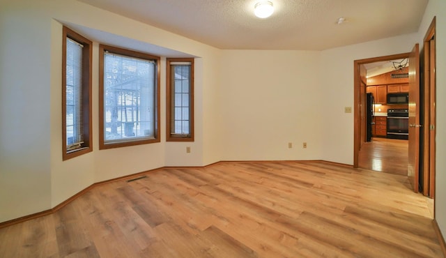 spare room with visible vents, a textured ceiling, light wood-type flooring, and baseboards