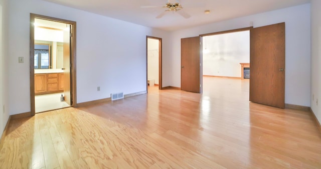 spare room with visible vents, a fireplace, baseboards, and light wood-style floors