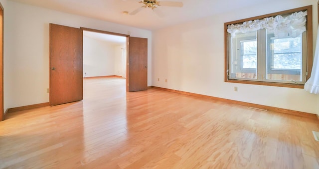 empty room with visible vents, ceiling fan, baseboards, and light wood-style floors