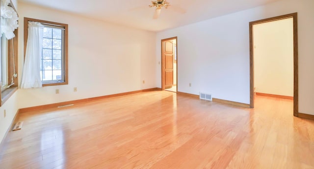 unfurnished room with light wood finished floors, visible vents, ceiling fan, and baseboards