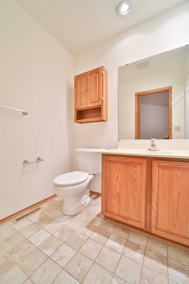 bathroom with visible vents, baseboards, toilet, and vanity