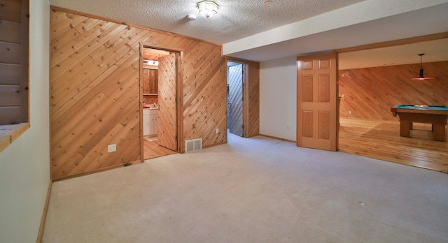 interior space with visible vents, a textured ceiling, wooden walls, and carpet floors