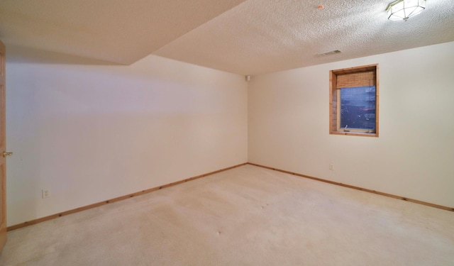 carpeted spare room with visible vents, baseboards, and a textured ceiling